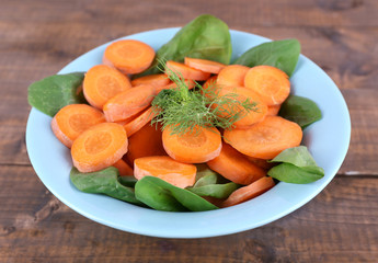 Slices of carrot, sorrel and dill in blue round bowl