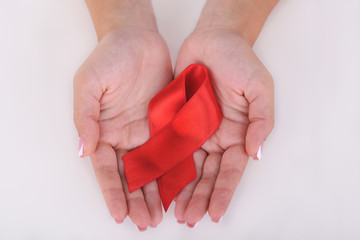 Woman with aids awareness red ribbon in hands isolated on white