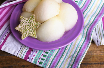Melon in plate on napkin on wooden background