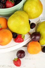 Ripe fruits and berries in bowl on table close up
