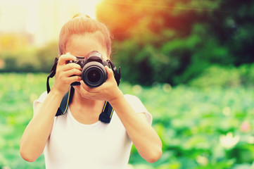 young woman photographer taking photo of blooming lotus at park 