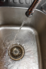 close up shot on water hose with water flowing from it. Shallow