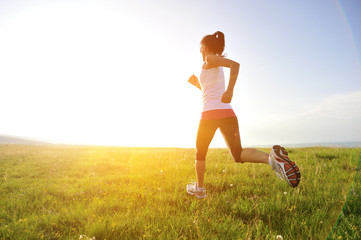 Runner athlete legs running on sunrise grass seaside