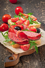 Sandwich with sausage, olive, tomato and arugula 