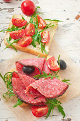 Sandwich with sausage, olive, tomato and arugula 