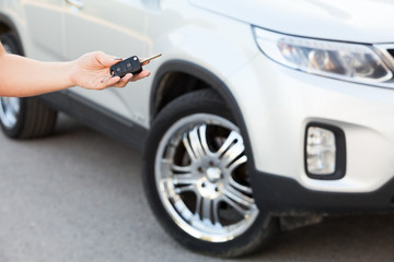Female hand holding car key with suv on background