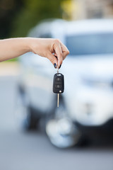 Car defocused on background and woman hand with key