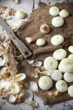 small golden onions with peel and some peeled on rustic set