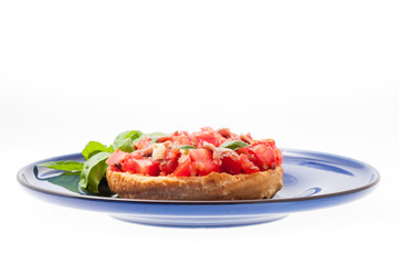 Frisella con pomodori rossi e acciughe su un piatto blu