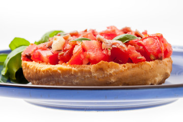 Frisella con pomodori rossi e acciughe su un piatto blu