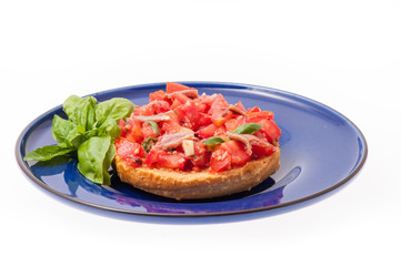 Frisella con pomodori rossi e acciughe su un piatto blu