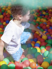 Fototapeta na wymiar Little boy playing in colorful balls playground