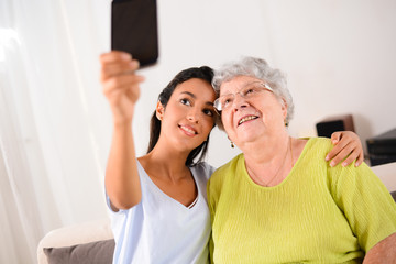two generation womans making a funny selfie together at home