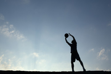 Silhouette of man playin basketball