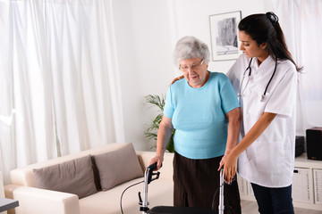 cheerful young rehab nurse helping elderly woman using a walker