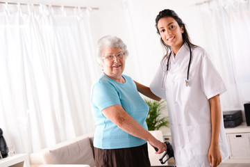 cheerful young rehab nurse helping elderly woman using a walker