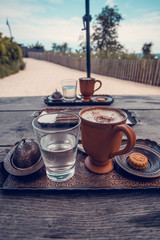 Fototapeta premium Чашка кофе, стакан воды и печенье на деревянном столе.
