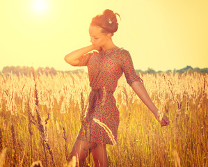Beautiful teenage girl in short dress posing on the field