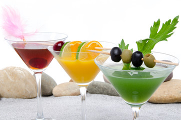 Orange, cherry and green vegetables cocktails on a beach environ