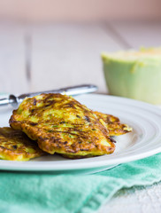 zucchini fritters on a white plate, green cloth