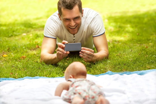 Father with baby In Park  taking selfie by mobile phone