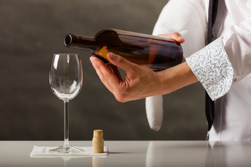 Man waiter pouring wine into glass.