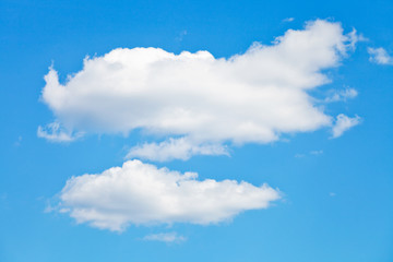 two puffy white clouds in blue sky