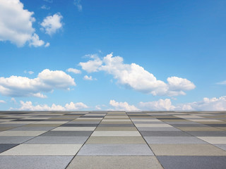 pavement with grey tiles and blue sky with clouds