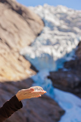 Hand with ice and Briksdal glacier - Norway