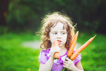 Happy little girl with bunch of carrots.