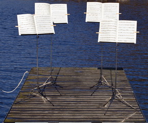 Vier Notenständer auf einem Steg am See