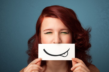 Pretty young girl holding white card with smile drawing