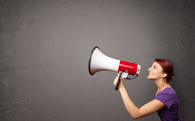 Girl shouting into megaphone on copy space background