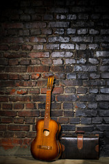 Fototapeta na wymiar guitar and retro bag on brick wall background