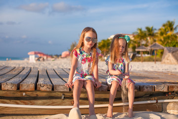 Two happy little girls enjoy vacation on white beach