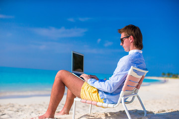 Young man working on laptop at tropical beach