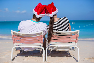 Young couple in Santa hats enjoy beach vacation