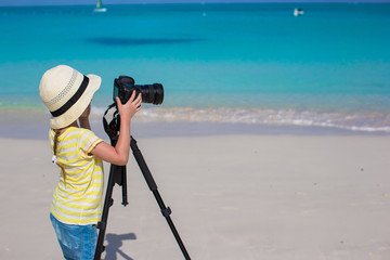 Little girl shooting with camera on tripod during her summer