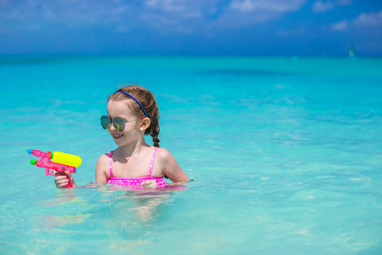 Happy little girl playing with toys during caribbean vacation