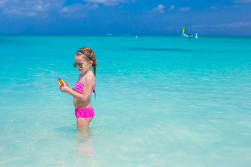 Cute little girl playing with toys during caribbean vacation