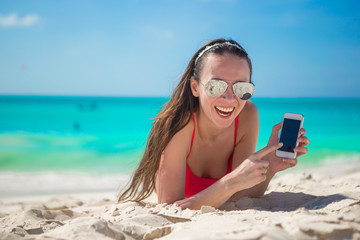 Young woman lying on white sand and talking by cell phone