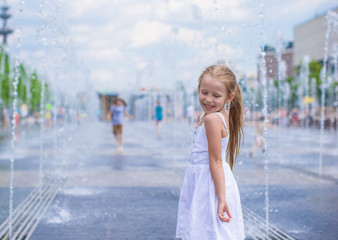 Little girl have fun in open street fountain at hot summer day