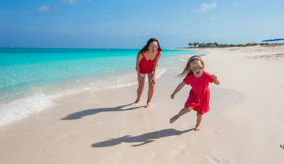 Young mother and little girl have fun at tropical beach