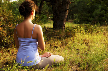 Young woman practicing yoga in the forest