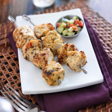 two grilled chicken sishkabobs with cucumber salad