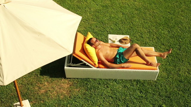 Young man sunbathing on sunbed in the garden