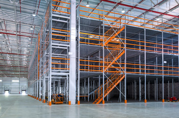 Mezzanine inside big automated warehouse, interior with modern tall shelving and racking