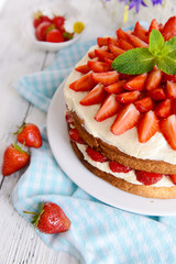 Delicious biscuit cake with strawberries on table close-up