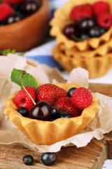 Tasty tartlets with berries on wooden table