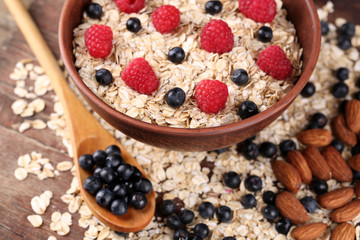 Big brown bowl with oatmeal and berries on a wooden table